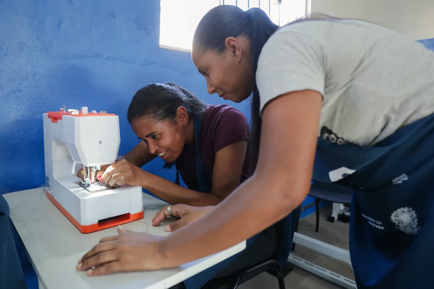 Instrutora orientando aluna na máquina de costura no Costurando Amor