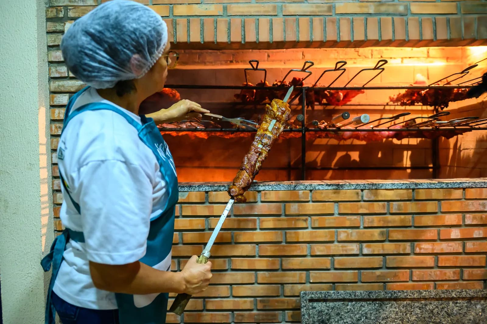 Aluna do Núcleo Farmabase preparando espetos de carne na churrasqueira