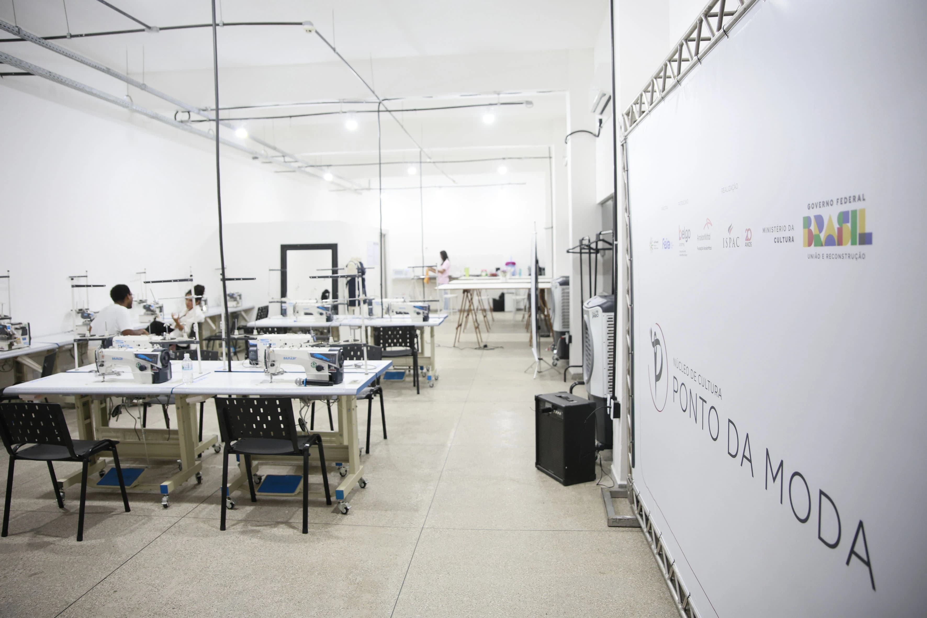Estudantes no ateliê cortando tecidos e preparando modelagens de roupas